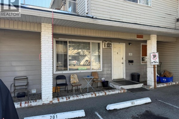 Front entrance of unit 101 with a white door and windows showing reflections of cars in a parking lot. - 3710 24 Avenue Unit# 101, Vernon