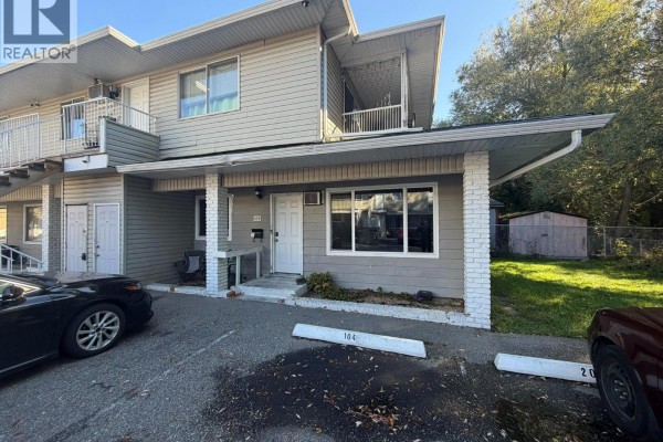 Apartment building exterior showing unit 104 entrance with covered walkway and parking. - 3710 24 Avenue Unit# 104, Vernon