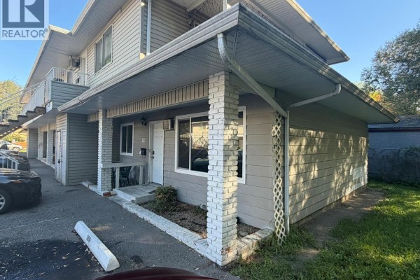 Exterior view of apartment building with unit 104 entrance and parking area. - 3710 24 Avenue Unit# 104, Vernon