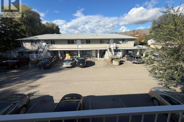 Aerial view of apartment building complex with parking lot and surrounding trees. - 3710 24 Avenue Unit# 202, Vernon