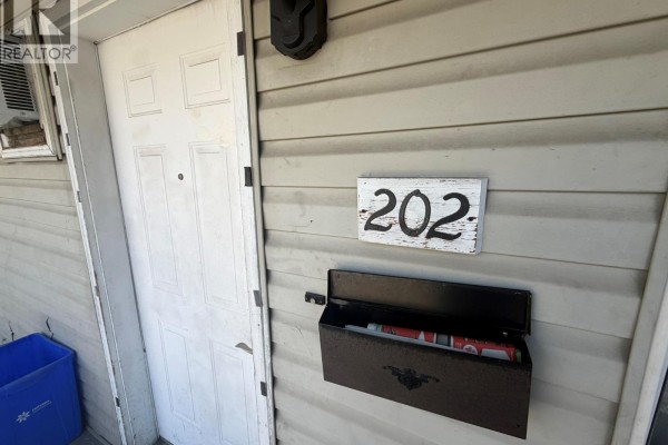 Close-up of building exterior showing white door, mailbox, and unit number 202. - 3710 24 Avenue Unit# 202, Vernon