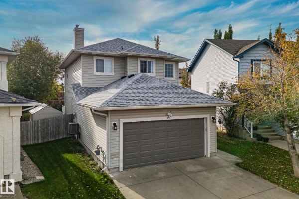 Lush green backyard with a tall wooden privacy fence, mature trees, and landscaping. - 3711 161 Av Nw, Edmonton