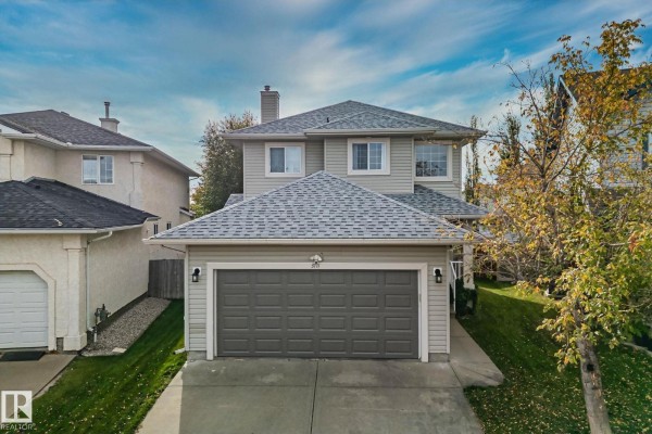 White kitchen cabinets with dark granite countertops, stainless steel appliances, and a glass tile backsplash. - 3711 161 Av Nw, Edmonton