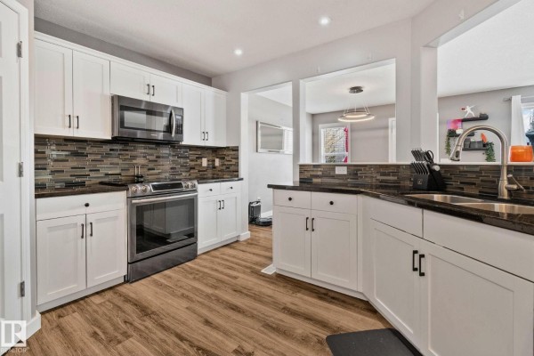 Kitchen corner with white cabinets, granite countertops, stainless steel dishwasher, and sink. - 3711 161 Av Nw, Edmonton