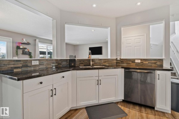 Close-up of a stainless steel range and microwave in a white kitchen with a tiled backsplash. - 3711 161 Av Nw, Edmonton