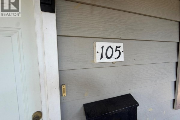 Close-up of unit number 105 sign on beige siding next to a white door. - 3712 24 Avenue Unit# 105, Vernon
