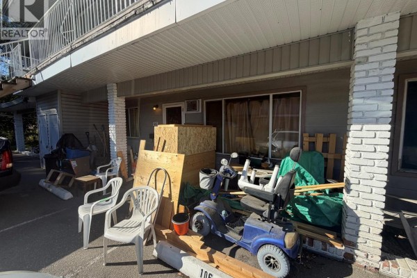 Exterior view of unit 106 entrance and covered walkway with clutter and construction materials. - 3712 24 Avenue Unit# 106, Vernon