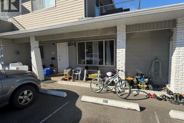 Exterior view showing the entrance to unit 108 with bicycles and a car. - 3712 24 Avenue Unit# 108, Vernon