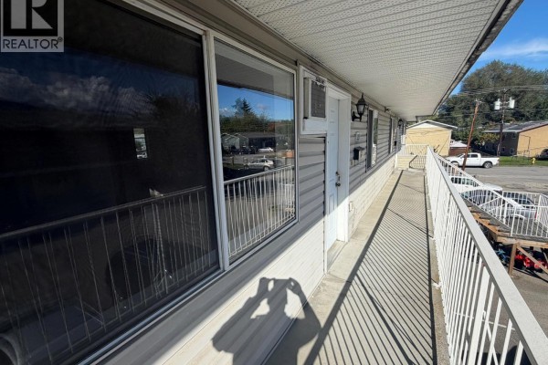 Exterior hallway with white railing and metal siding on building. - 3712 24 Avenue Unit# 205, Vernon