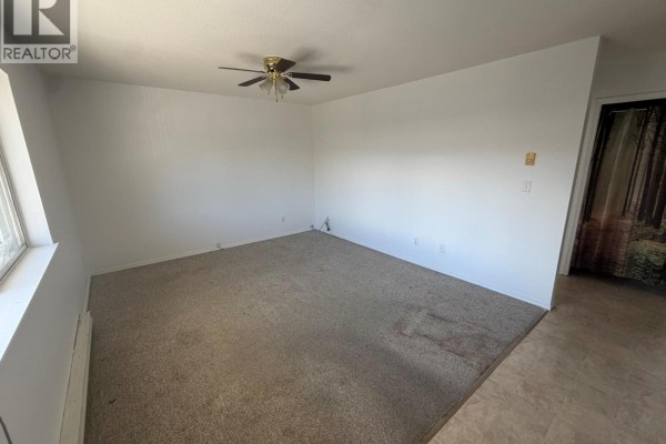 Living room with beige carpet, white walls, and a ceiling fan. - 3712 24 Avenue Unit# 205, Vernon