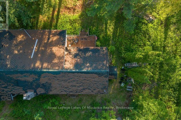 Aerial view of a long, shingled roof house with wooden decks surrounded by trees. - 3712 Brunel Road, Lake Of Bays
