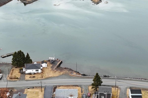 Aerial view of coastal properties with a bay, a dock, and houses lining a road. - 3712 Highway 206, Haut De La Baie