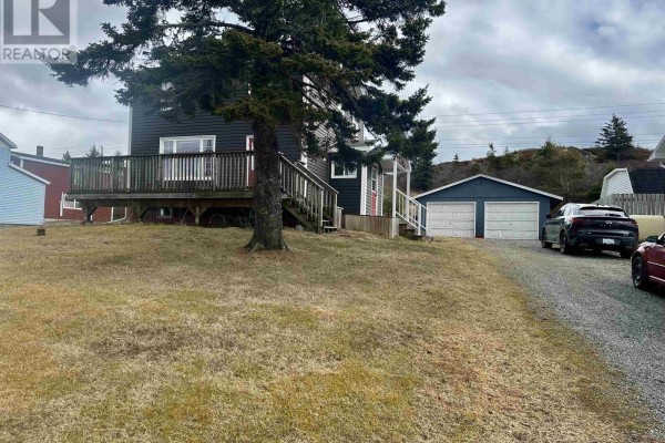 Side view of house with a wooden deck and stairs, a tree, and a detached two-car garage. - 3712 Highway 206, Haut De La Baie