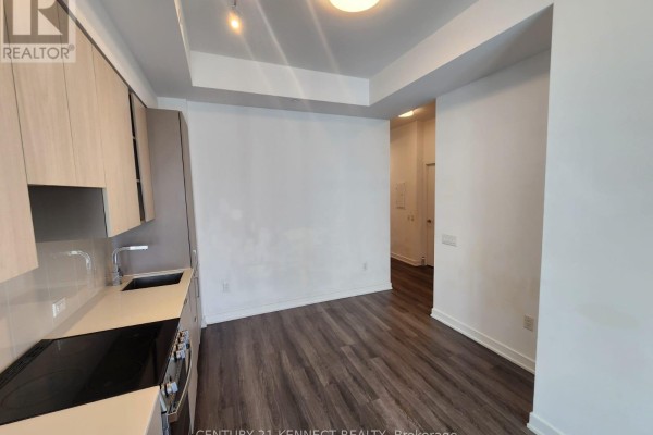 View of a kitchen and living area with dark wood floors and white walls. - 3713 - 3883 Quartz Road, Mississauga