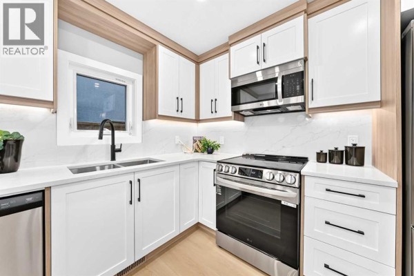 Kitchen with white shaker cabinets, stainless steel appliances, and a window above the sink. - 3715 14a Street Sw, Calgary