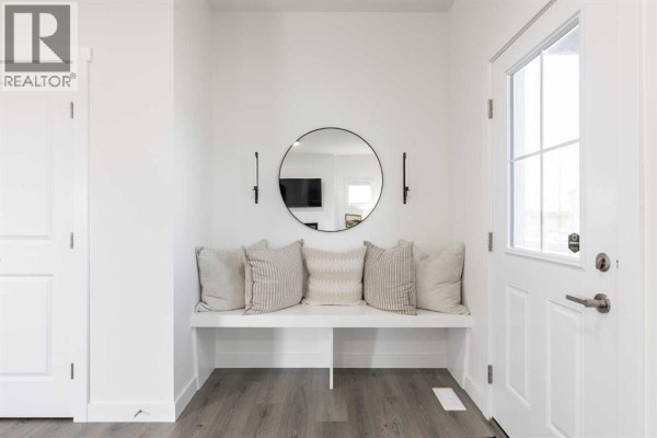 Entryway with white bench, decorative mirror, and grey wood-look flooring. - 372 Belmont Park Sw, Calgary