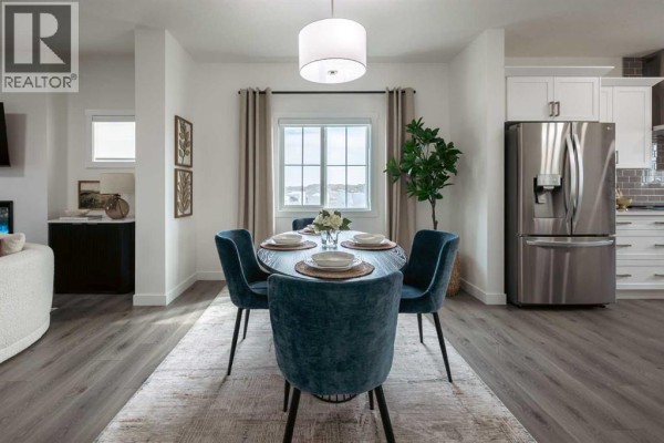 Dining area with dark oval table, blue chairs, and window overlooking exterior. - 372 Belmont Park Sw, Calgary