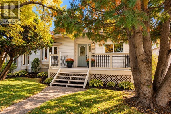 Close-up view of the house's light-colored siding, green front door with arched glass, and a weathered wooden porch. - 3721 44a Avenue, Red Deer