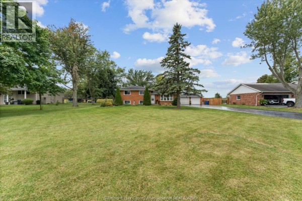 Wide view of a residential property with a brick house, garage, and large lawn. - 3724 Concession 3 Road North, Amherstburg