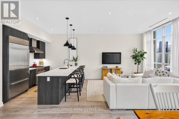 Kitchen with dark wood cabinets, island with bar stools, and stainless steel appliances. - 3725 Ferretti Court, Innisfil