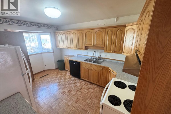 Kitchen with light wood cabinets, double sink, black dishwasher, white refrigerator and stove. - 3726 Normandy Avenue, Regina