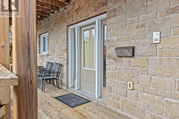 Wooden porch with seating outside the main entrance, featuring stone exterior. - 373 First Avenue E, North Bay