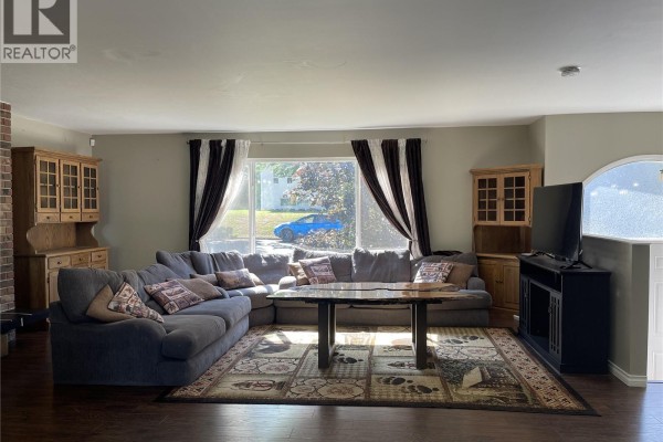 Living room with large sectional sofa, live edge coffee table, and brick fireplace. - 3731 Fowlie Cres, Port Alberni