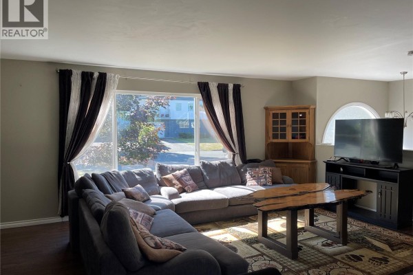 Spacious living room with sectional sofa, entertainment unit, and large window view. - 3731 Fowlie Cres, Port Alberni