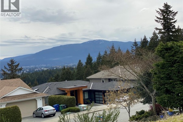Residential street with diverse homes, trees, and a view of snow-capped mountains. - 3733 Belaire Dr, Nanaimo
