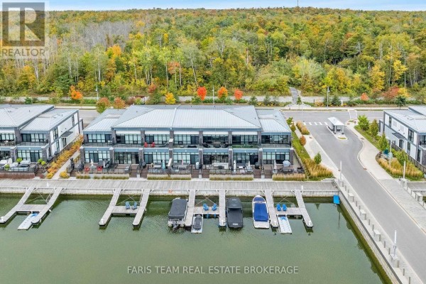 Aerial view of a townhouse complex on a canal with boats docked. - 3733 Riva Avenue, Innisfil