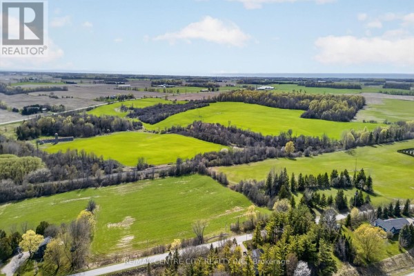 Aerial perspective of rolling green fields and wooded areas at 37332 Cutline Road. - 37332 Cutline Road, Central Huron