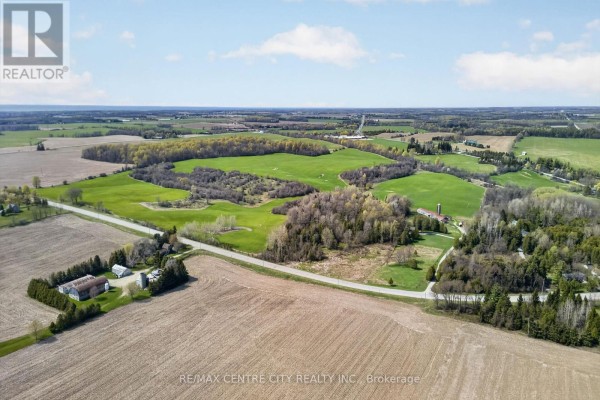 Overview of 37332 Cutline Road property, featuring fields, trees, and distant buildings. - 37332 Cutline Road, Central Huron