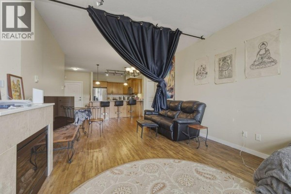 Living room view with a curtain, seating area, and open layout towards the kitchen. - 3739 Casorso Road Unit# 316, Kelowna