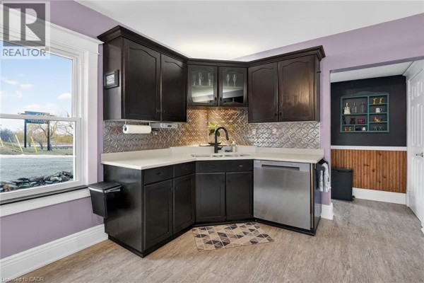 Kitchen and dining area with dark cabinets, stainless steel appliances, and a dining table with floral chairs. - 3745 King Street, Vineland