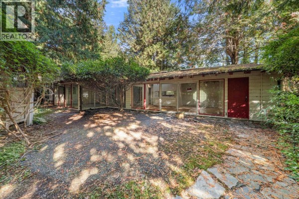 Exterior of a single-story house with a long wall of windows and two red doors. - 3745 Southridge Avenue, West Vancouver