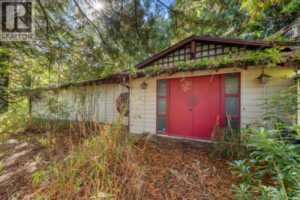 Close-up of a large red double door with decorative panels, set in a beige wall with wood trim. - 3745 Southridge Avenue, West Vancouver
