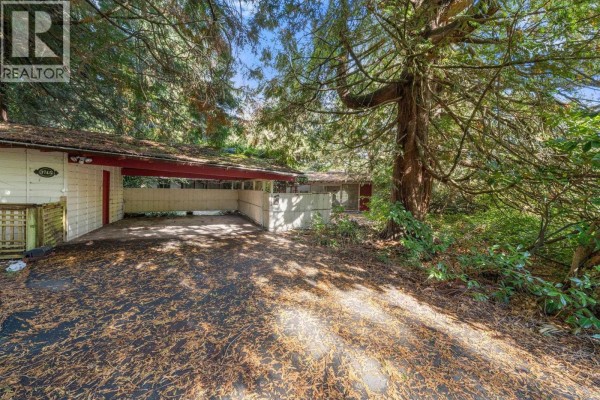 Driveway leading to a covered carport and the side of a house surrounded by trees. - 3745 Southridge Avenue, West Vancouver