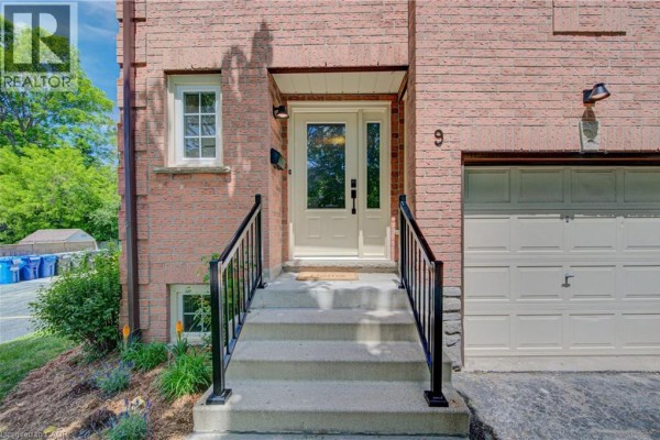 Close-up of unit 9 entrance with concrete steps, black railings, and beige door. - 375 Holiday Inn Drive Unit# 9, Cambridge
