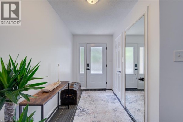 Foyer with white walls, console table, mirrored closet doors, and a patterned rug. - 375 Holiday Inn Drive Unit# 9, Cambridge