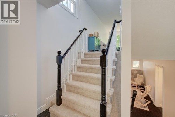 Carpeted staircase with white spindles, black railings, and view of a living area. - 375 Holiday Inn Drive Unit# 9, Cambridge
