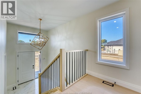 Interior view of the foyer with a contemporary chandelier, a white door, and a large window. - 375 Mayrand Street, Lasalle