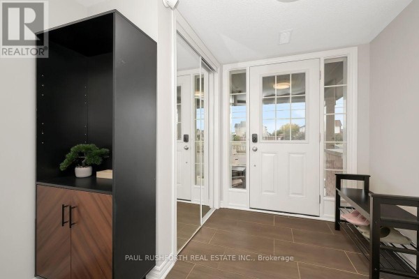 Foyer with tiled floor, white double doors, and a black and wood cabinet with mirrored closet doors. - 375 Sweetfern Crescent, Ottawa