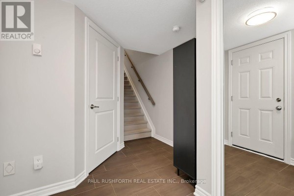 Foyer area with tiled floor, white doors, and carpeted stairs leading up to the next level. - 375 Sweetfern Crescent, Ottawa