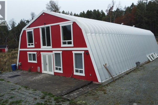 Side view of the red barn structure showing two stories of windows and metal roof. - 3750 Yellow Point Rd, Nanaimo