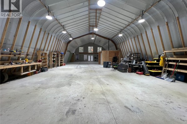 Interior of a large open barn with concrete floor, metal arched ceiling, and workbenches. - 3750 Yellow Point Rd, Nanaimo