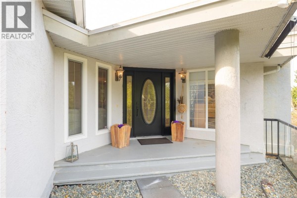 A bedroom with a large bed, fireplace, ceiling fan, and a sliding glass door with ocean view. - 3758 Panorama Cres, Chemainus