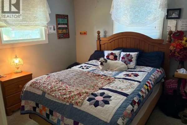 Small bedroom with a twin bed, floral bedding, dark nightstand, and a framed portrait on the wall. - 376 Brown Street, Dresden