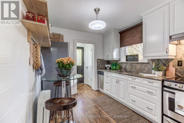 Kitchen with white cabinets, granite countertops, stainless steel appliances, and a small round glass table. - 376 Glen Manor Drive, Toronto