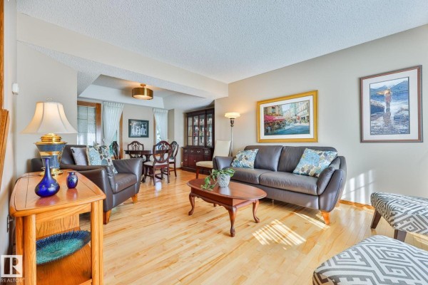 Living room with leather sofas, wooden floors, and dining room in the background. - 3764 30 St Nw, Edmonton