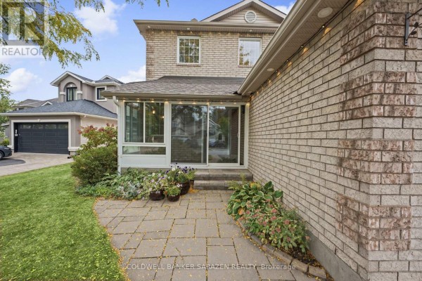 View of the side of the house with a sunroom addition and paved patio. - 3766 Mountain Meadows Crescent, Ottawa
